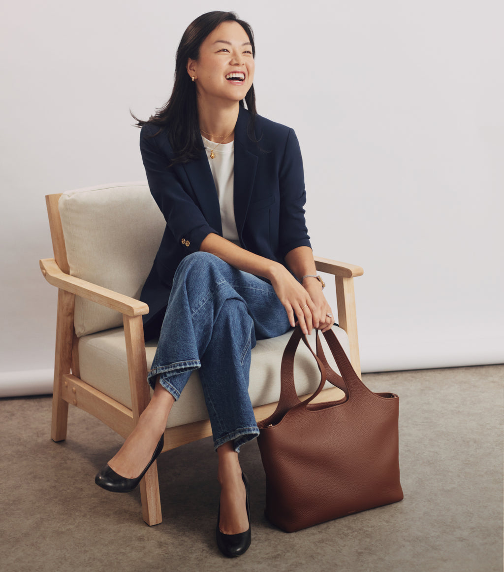 Person seated with a tote bag on the floor by the chair.