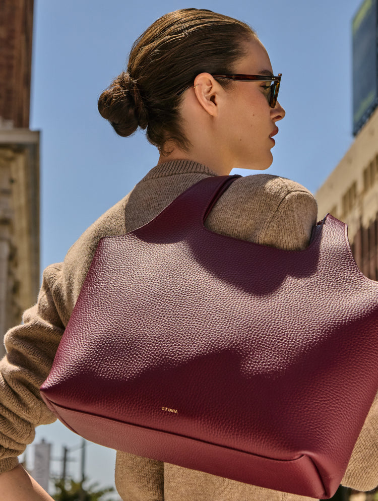 Person outdoors carrying a large bag over shoulder wearing sunglasses