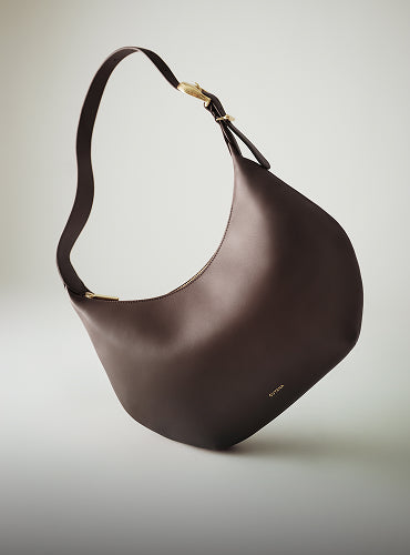 Curved shoulder bag with wide strap and gold zipper detail.