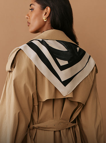 Person wearing a trench coat with a patterned scarf on back.
