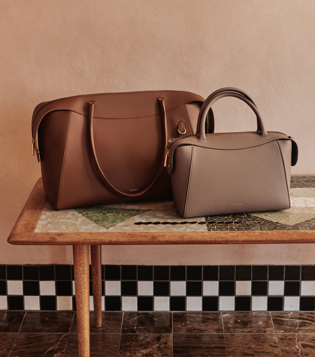 Two handbags on a wooden table.