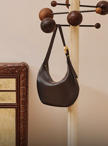 Bag hanging on a coat rack near a decorated piece of furniture.