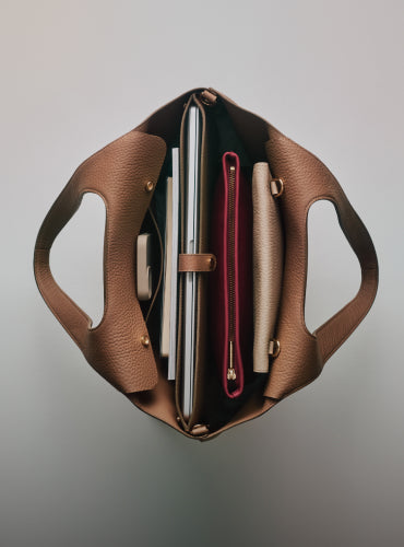 Open handbag with laptop, pouches, and a notebook inside.