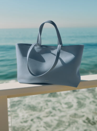 Tote bag on a railing by the ocean.