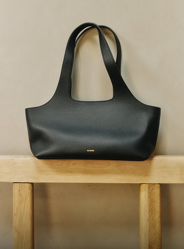 Handbag with long handles on a wooden bench.