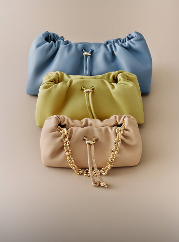 Three gathered clutches stacked vertically with drawstrings and chain detail.