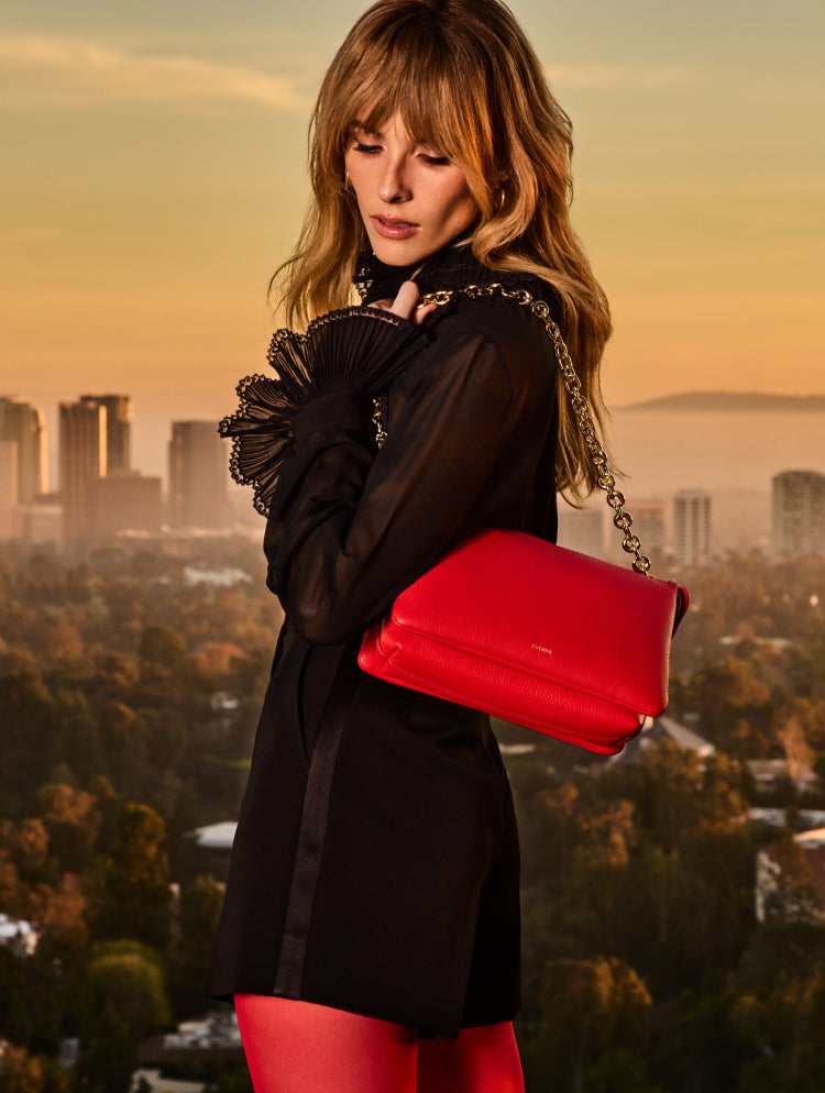 Person in outfit with bag over shoulder, urban skyline background.