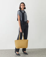 Person with a handbag wearing a sweater over a shirt and pants