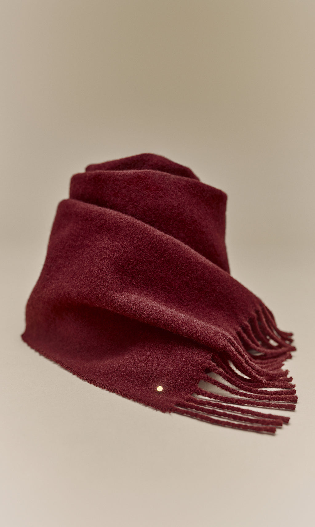Fringed scarf folded on a plain background