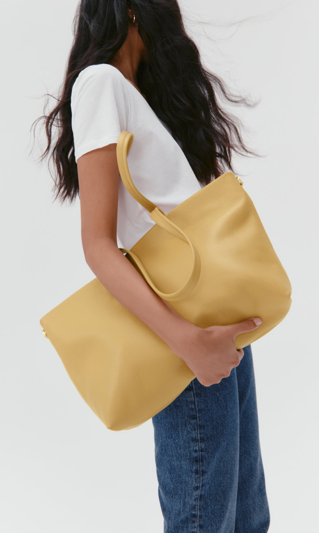 Person holding a large handbag wearing a casual outfit.