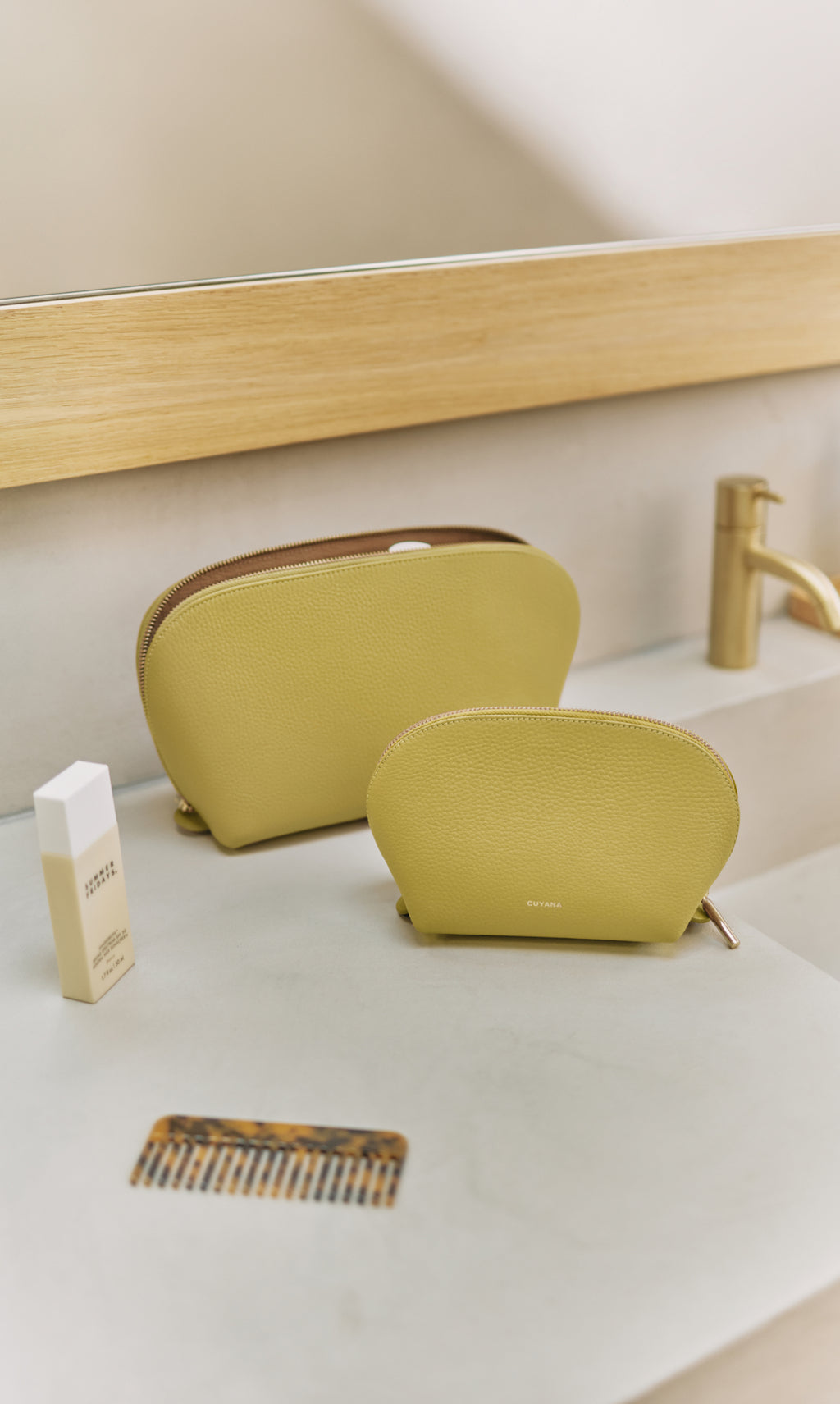 Two toiletry bags on a bathroom counter with a comb and a bottle nearby.