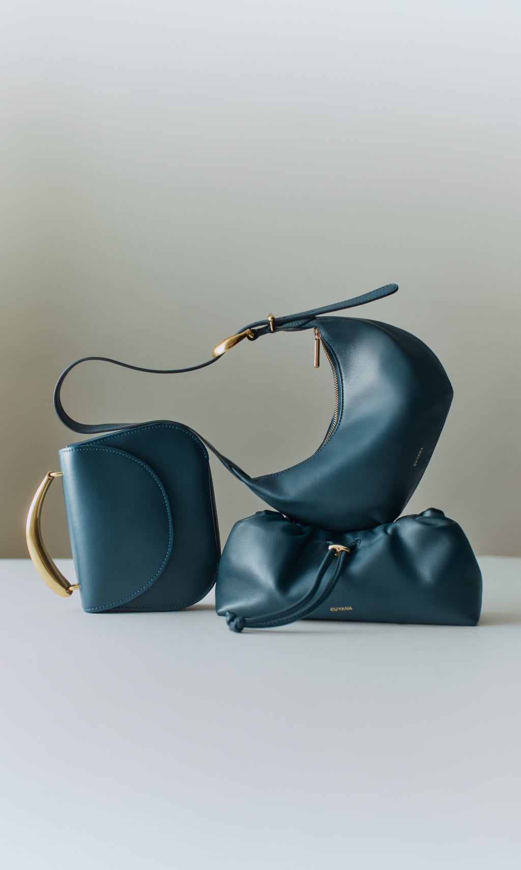 Three elegant leather handbags with unique shapes on display.