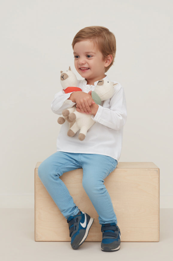 Child sitting and hugging two stuffed toys.