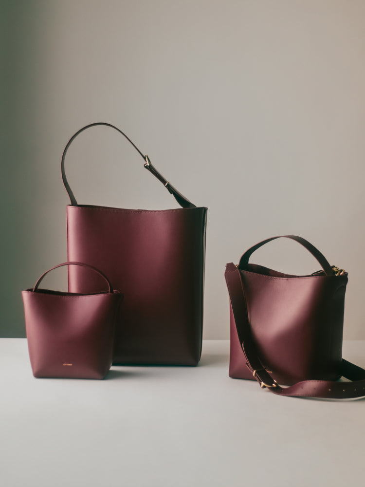 Three leather handbags in varying sizes on a flat surface.