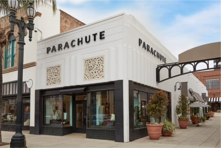 Storefront of Parachute with large windows and potted plants outside.