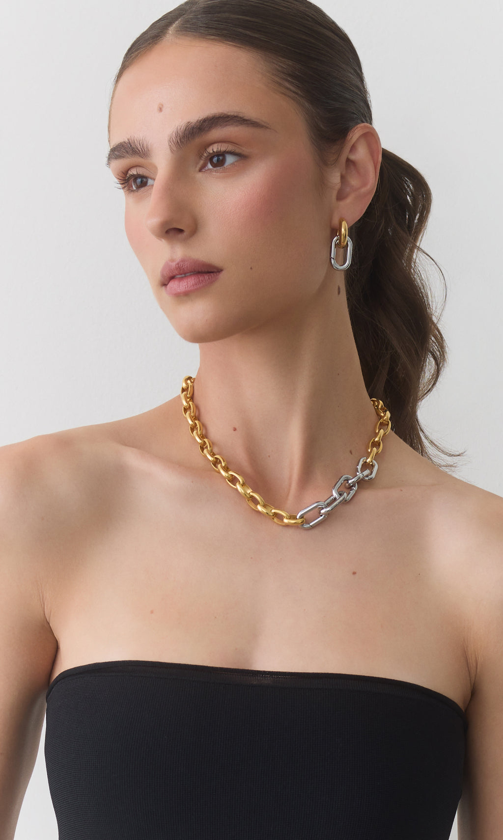 Woman wearing a chain necklace and shoulder-length earrings.