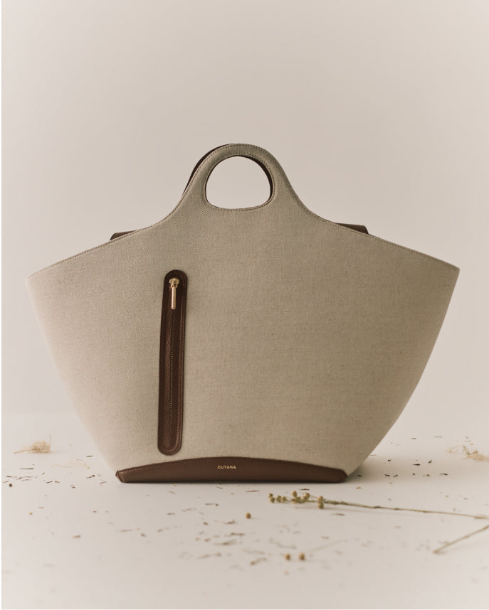 Large tote bag with circular handles and small zipper pocket.