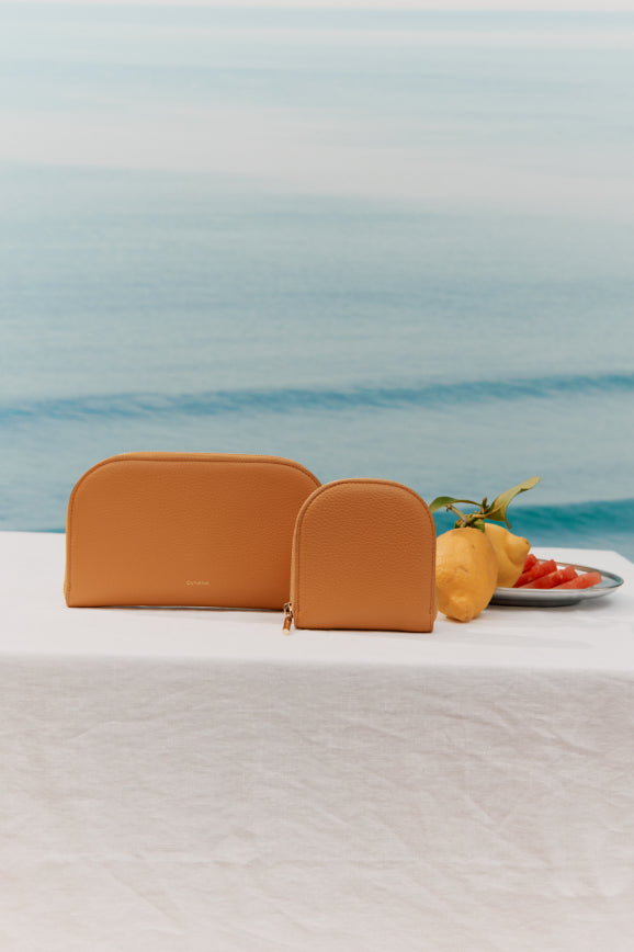 Two wallets on a table with lemons and strawberries next to a sea background.