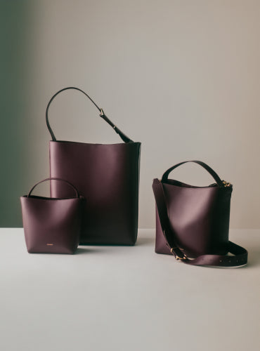 Three elegant handbags of varying sizes on a surface.