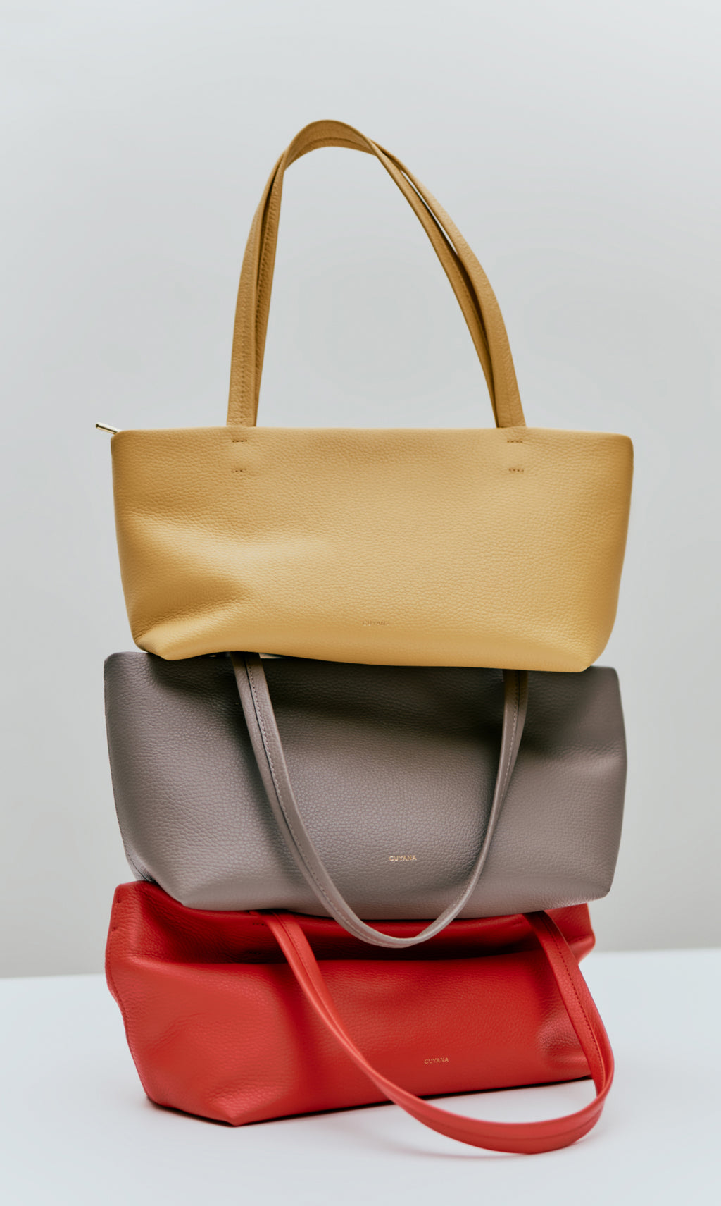 Three tote bags stacked on a surface.