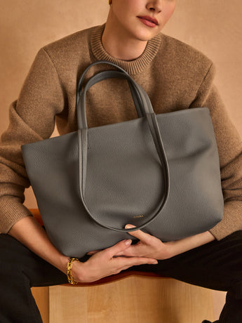 Person holding large tote bag while sitting