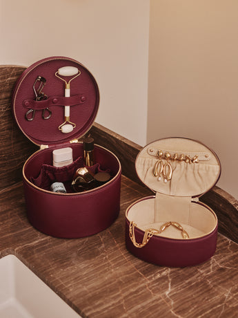 Two open round cases holding toiletries and jewelry on a countertop.