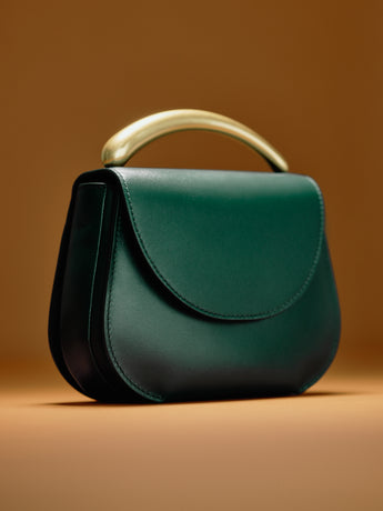 Handbag with a curved handle on a plain background
