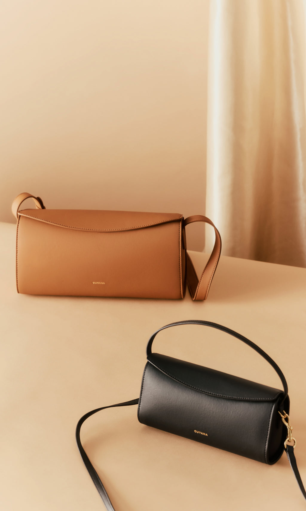Two handbags with straps displayed on a plain surface.
