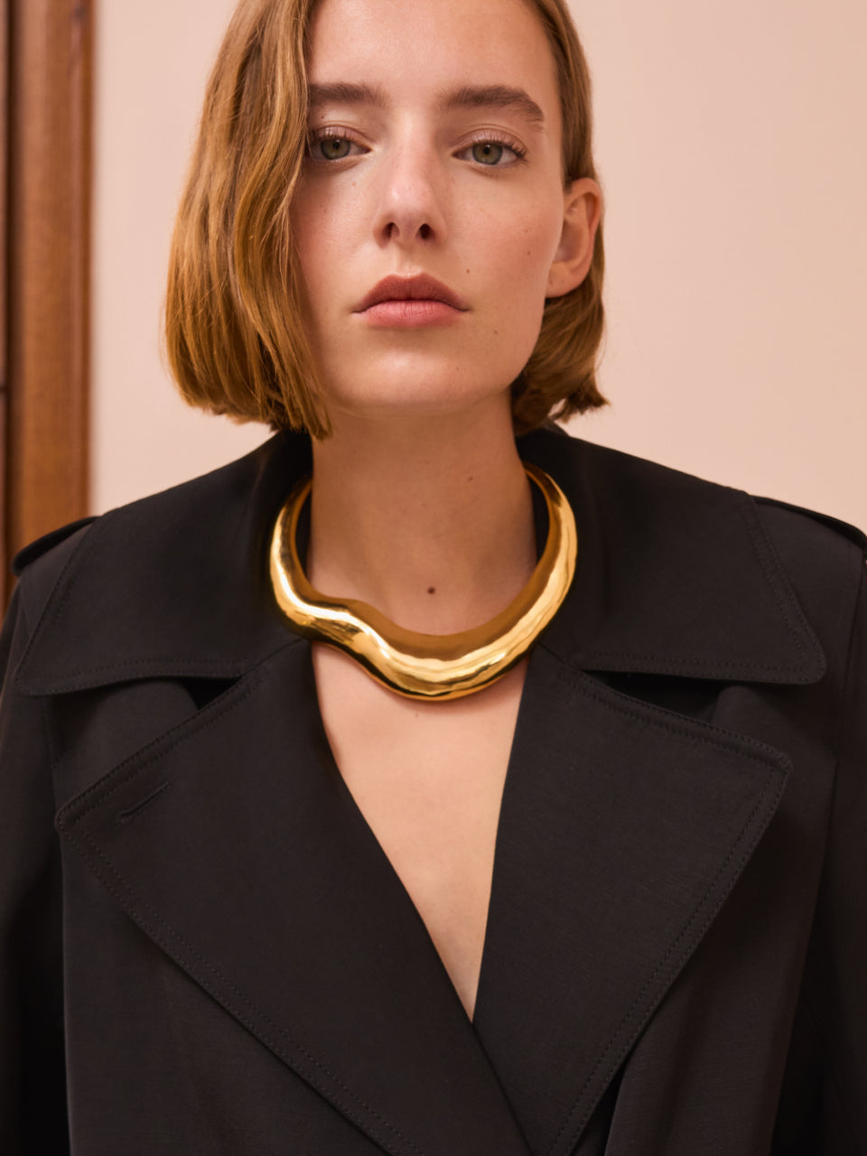 Person wearing a large necklace and coat.