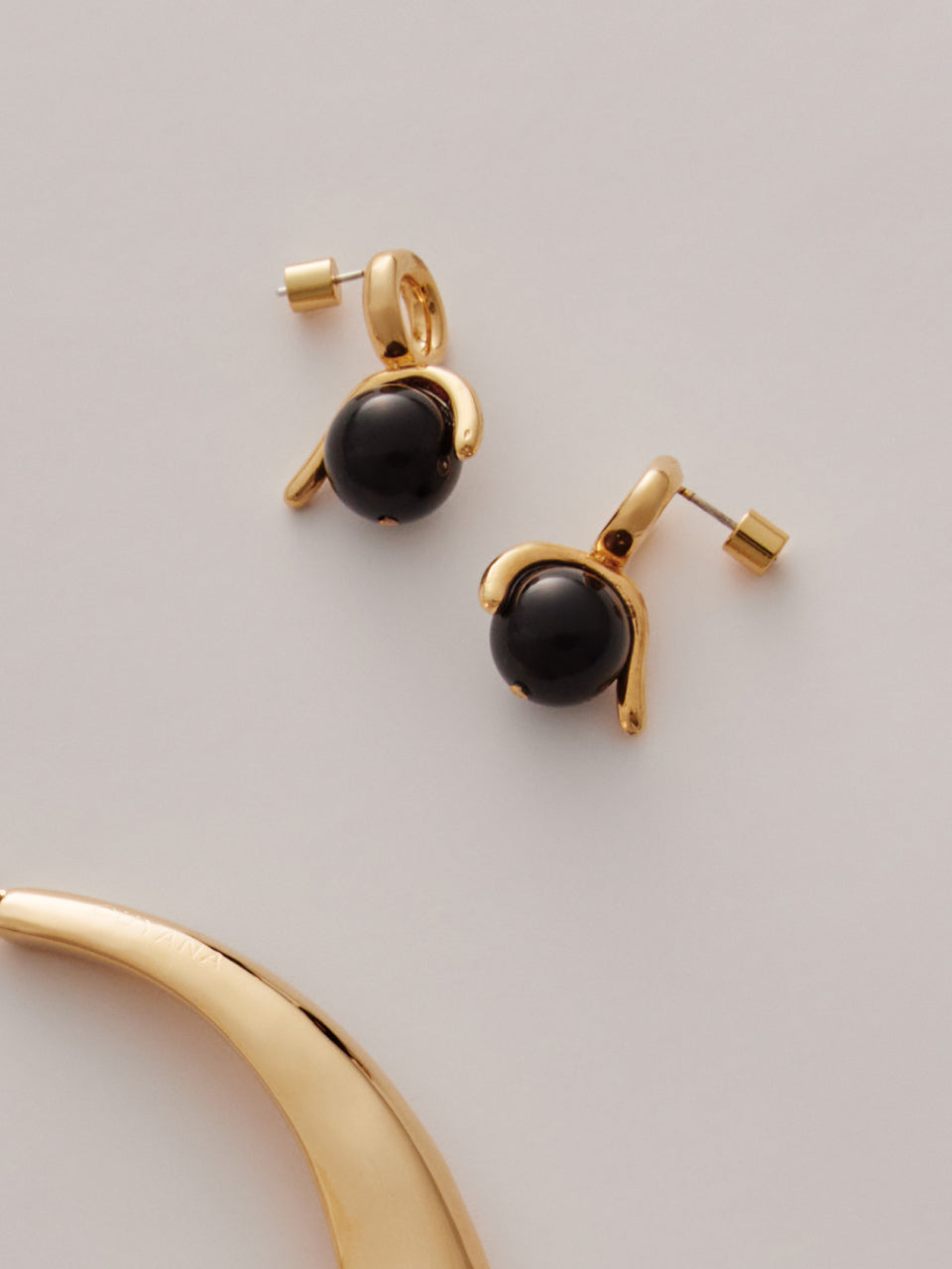 Gold and black stone earrings on a plain surface.