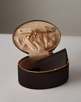 Oval jewelry case holding earrings and necklace, small pouch inside.