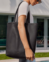 Person holding a large tote bag in front of a building.