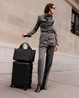 Person standing with a suitcase and a travel bag