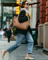 Person walking on city street carrying large tote bag over shoulder