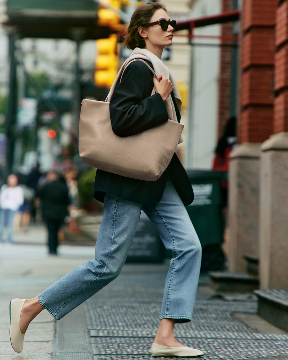 Person walking on city street carrying large tote bag over shoulder