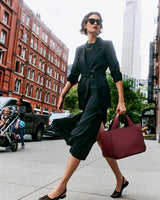 Person in a suit walking on a city street carrying a large handbag