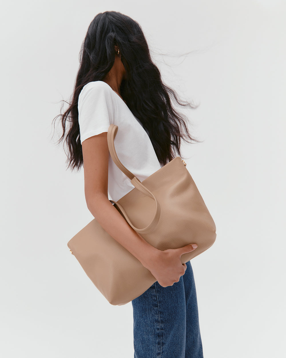 Person holding a large handbag wearing a white shirt and jeans