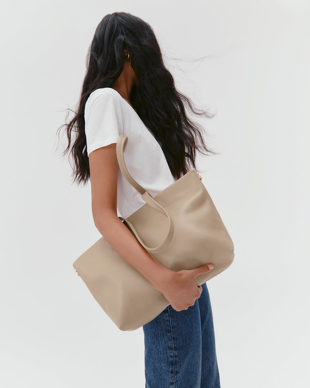 Person holding a large tote bag, wearing a t-shirt and jeans.