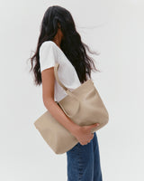 Person holding a large tote bag, wearing a t-shirt and jeans.