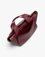 A dark red handbag with dual handles and multiple compartments, viewed from the top.