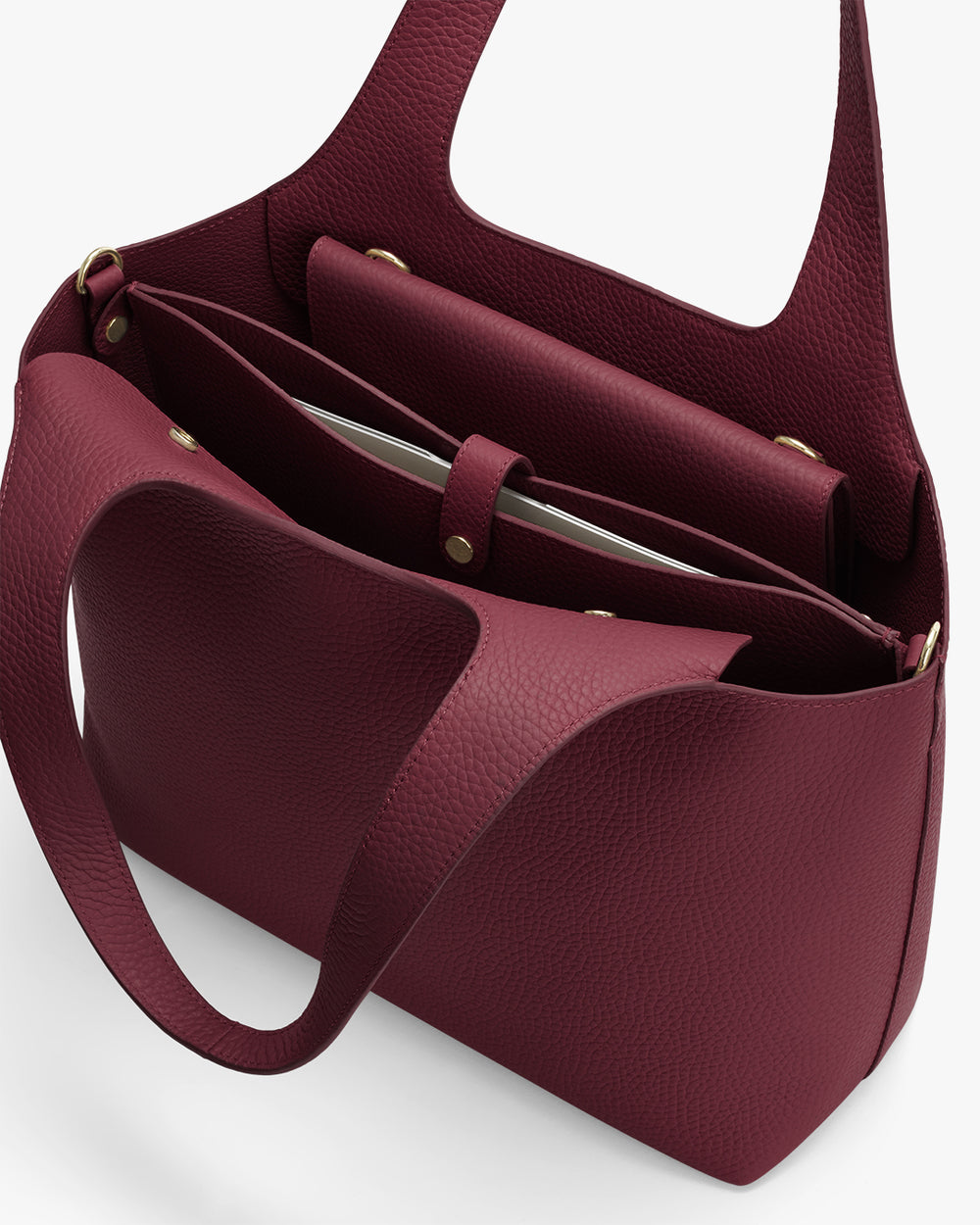 Handbag with multiple compartments and a handle, containing items inside.