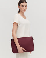 Woman holding a large clutch bag against her side.