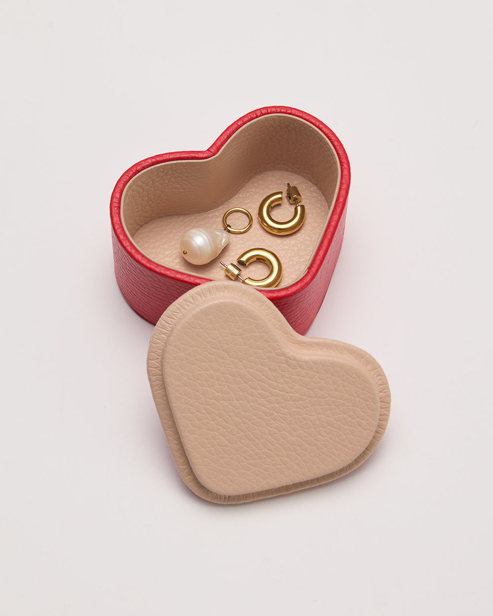 Heart-shaped jewelry box with earrings and a pearl.