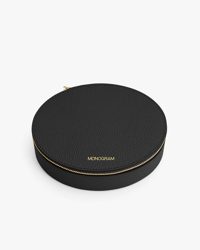 Round zippered case with monogram text on top.