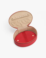 Open round leather jewelry box with zipper and snap-button enclosure.