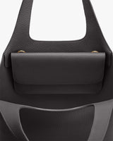 Close-up of a handbag with a front pocket and two handles.
