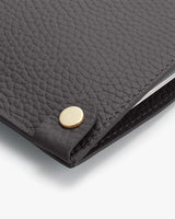 Close-up of a textured leather folder with a round metal button detail.