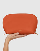 Hand holding a semi-circular pouch with a zipper.