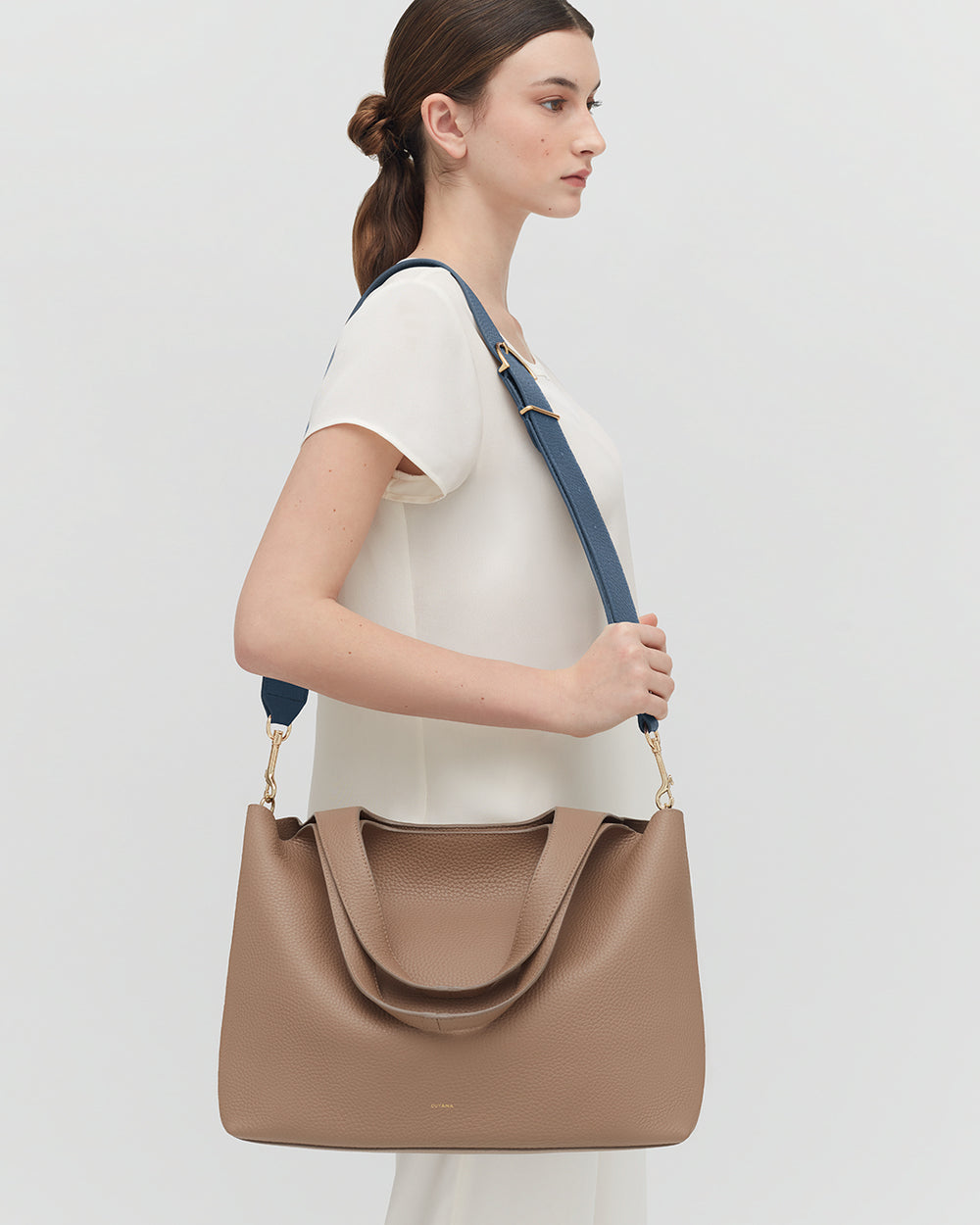 Person holding a large handbag with a shoulder strap.