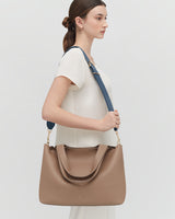 Person holding a large handbag with a shoulder strap.